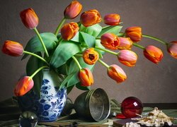 Tulipany w wazonie obok kielicha i szklanych kul