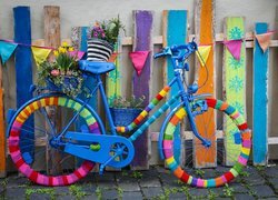 Udekorowany rower oparty o kolorowy płot
