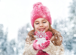 Uśmiechnięta dziewczynka z płatkiem śniegu w dłoniach