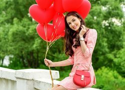 Uśmiechnięta kobieta z czerwonymi balonami