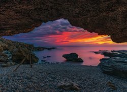 Widok z jaskini na morze o zachodzie słońca