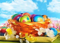 Wielkanocna dekoracja z pisankami w koszyczku i kwiatami