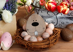 Wielkanocna dekoracja z zającem w koszyku wśród jajek i kwiatów