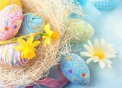 Wielkanocna kompozycja z kolorowych pisanek w gnieździe i żonkili