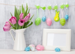 Wielkanocna kompozycja z tulipanami w dzbanku i wiszącymi pisankami