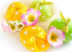 Wielkanocne pisanki z kokardkami udekorowane kwiatami prymulki