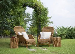 Wiklinowe fotele i stoliki pod drzewami w ogrodzie