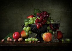 Winogrona i jabłka na parterze obok kieliszka z winem