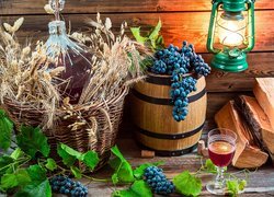 Winogrona na beczce obok lamy naftowej i butli z winem