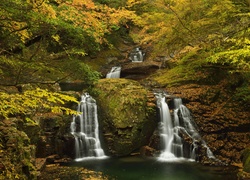 Wodospad płynący wśród skał w jesiennym lesie