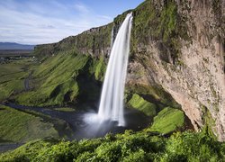 Wodospad Seljalandsfoss i zielone łąki w Islandii