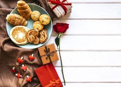 Wypieki na talerzu obok prezentów i róży