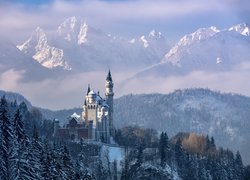 Zamek Neuschwanstein w niemieckich Alpach zimą spowity mgłą
