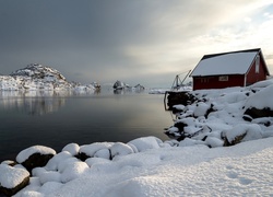 Zimowy krajobraz z domem nad rzeką i górami w tle
