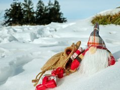 Zimowy skrzat z workiem prezentów w śniegu
