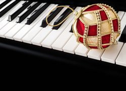 Złoto-czerwona bombka na klawiszach pianina