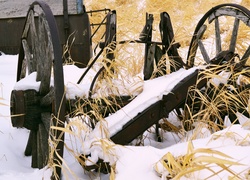 Zniszczona maszyna rolnicza w trawie przysypana śniegiem