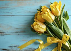 Żółte tulipany ze wstążką na niebieskich deskach