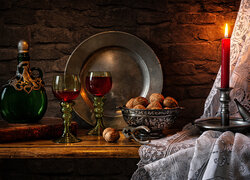 Kieliszki z winem obok orzechów w blasku świecy