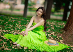 Kobieta w zielonej sukience siedząca na trawie