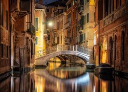Oświetlone nocą domy i most nad kanałem w Wenecji