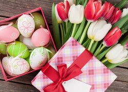 Pudełko z pisankami obok kolorowych tulipanów