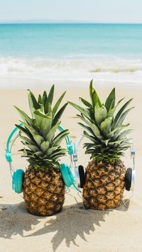 Ananasy ze słuchawkami na plaży
