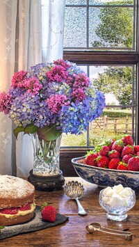 Bukiet kwiatów obok ciasta i truskawek przy oknie