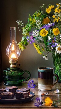 Bukiet kwiatów obok lampy i kubka