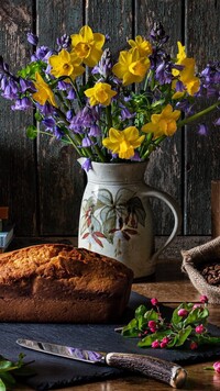Chleb obok wiosennych kwiatów w dzbanku