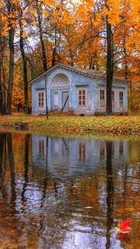 Domek w parku nad stawem jesienią