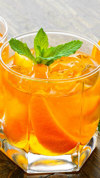 Drink w szklance z pomarańczą i miętą