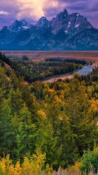 Drzewa nad rzeką i góry Teton Range pod chmurami