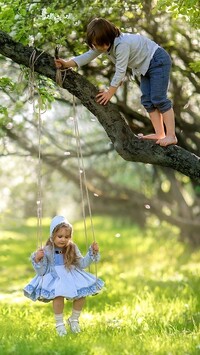 Dziewczynka na huśtawce i chłopczyk na drzewie
