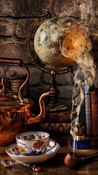 Filiżanka i czajnik obok globusa i dymiącej fajki