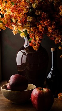 Jabłka obok wazonu z kwiatami