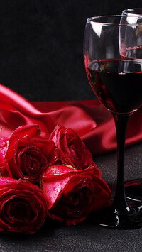 Kieliszki z czerwonym winem obok róż