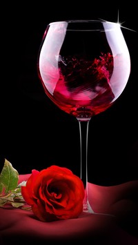 Kiliszek ciemnego wina z czerwoną różą