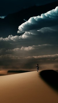 Kłębiaste chmury nad samotnym wędrowcem na pustyni
