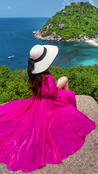 Kobieta w różowej sukni na skale nad morzem