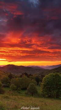 Kolorowe niebo nad górami i drzewami