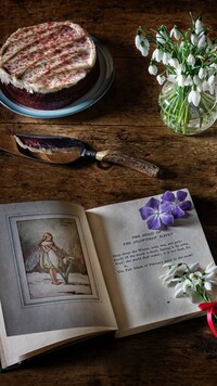 Książka obok ciasta i kwiatków na stole