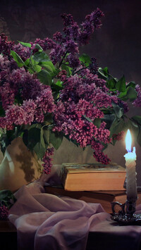 Kwiaty bzu obok książki i świecy na stole