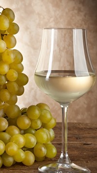Lampka białego wina obok winogron