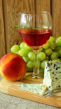 Lampka wina obok sera i brzoskwini