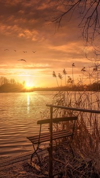 Ławeczka nad jeziorem o zachodzie słońca