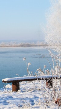 Ławka w śniegu nad jeziorem