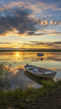 Łódka na brzegu jeziora o zachodzie słońca