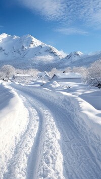 Ośnieżone domy i zaśnieżona droga na tle gór w oddali