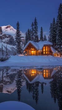 Oświetlony dom w śniegu nad jeziorem Emerald Lake